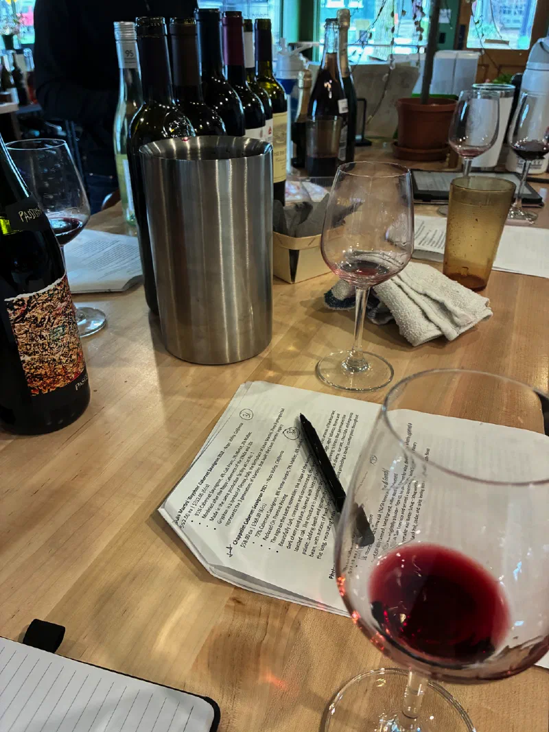 Tasting room counter — bottles, wine glasses, and a printed tasting guide with notes